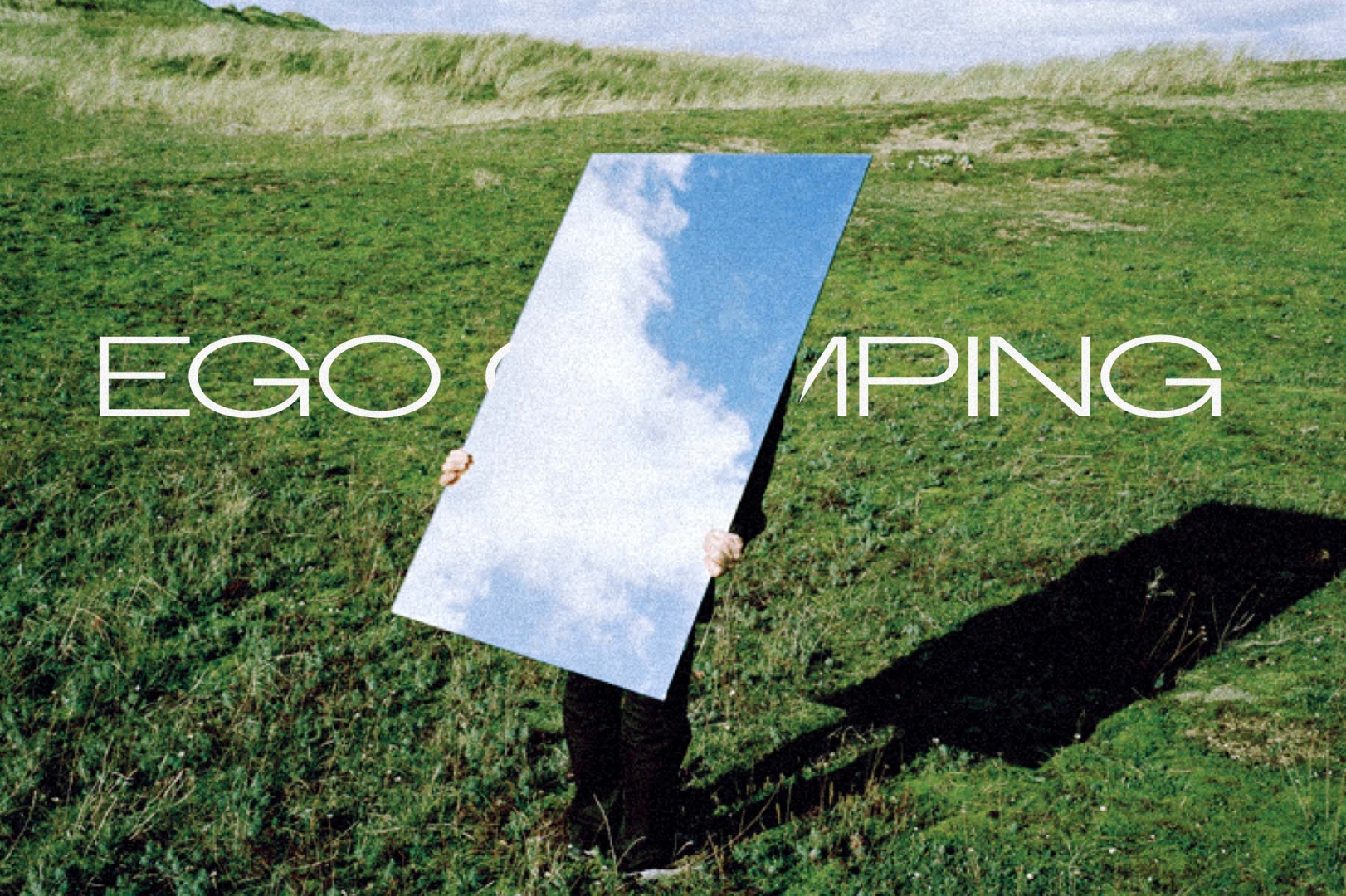 EGO Camping identity set over a grassy landscape with a mirror reflecting the sky