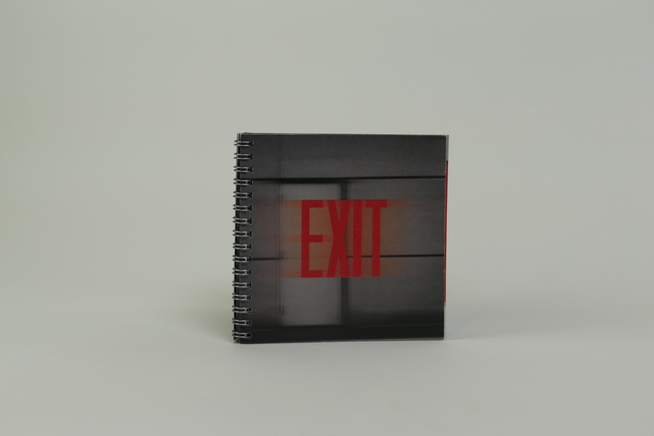 The spiral-bound EXIT book standing against a pale studio background
