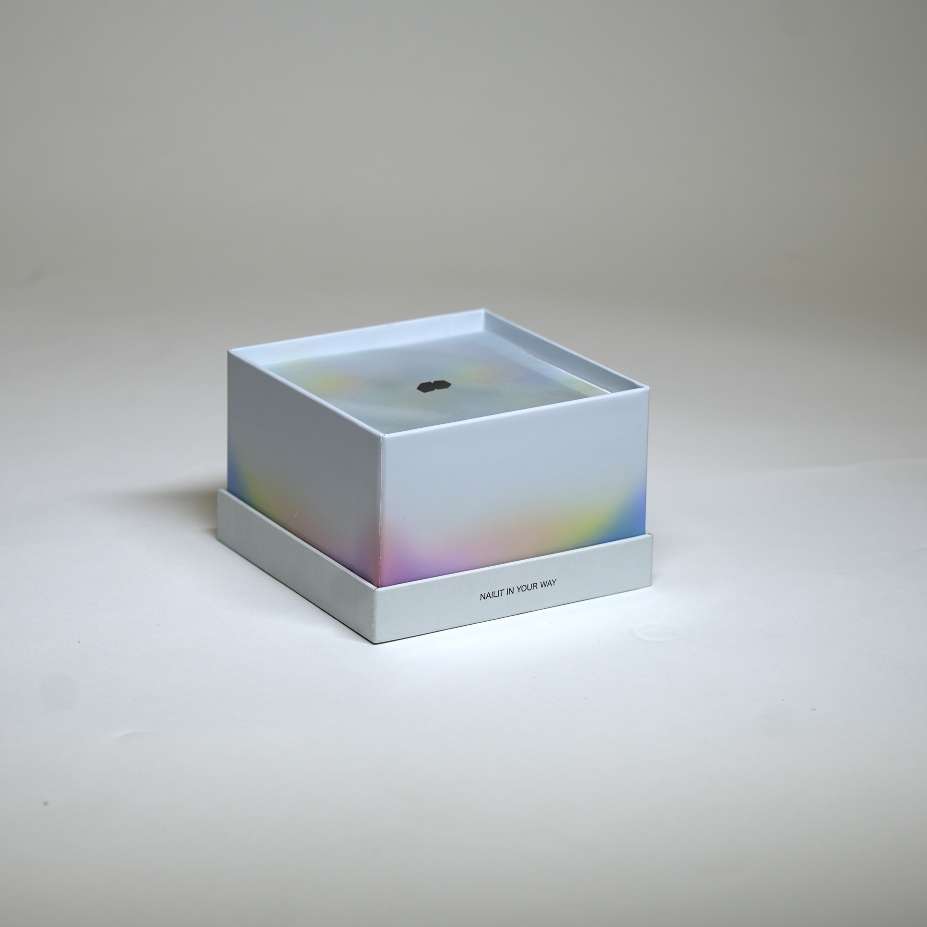 Primary NAILIT box photographed as a square white object with subtle iridescent colour